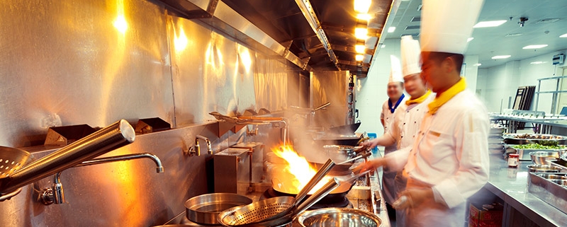 Multiple Asian chefs cooking over woks