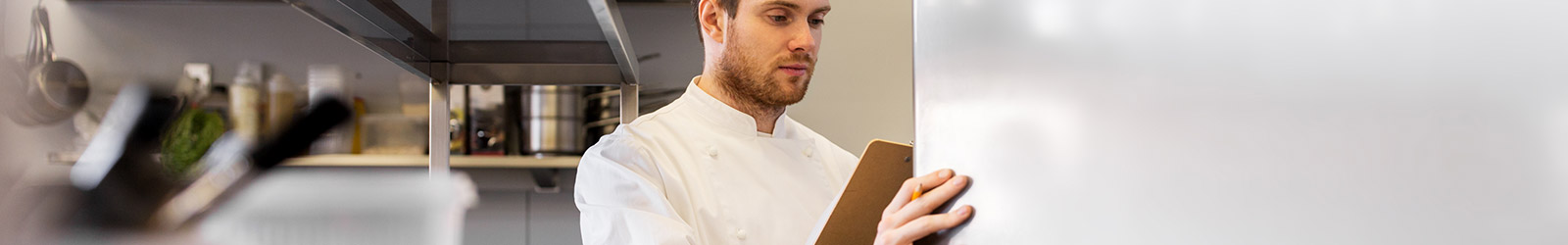 A chef consulting the contents of an industrial refrigerator