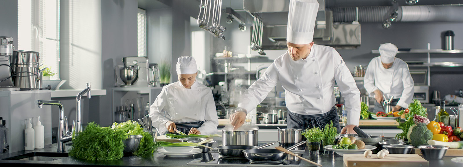 Chefs working in a gleaming stainless steel kitchen